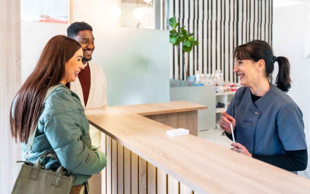 Patient speaking with friendly receptionist at front desk about payment options and special offers at Manassra Dental San Jose