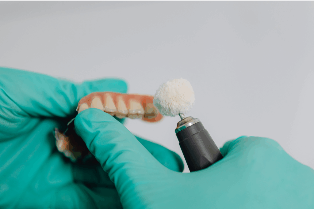 Dental professional in gloves using a rotary tool to polish a custom denture or restoration, illustrating the precision of **Expert Prosthodontontic Care** at Manassra Dental in San Jose, CA.