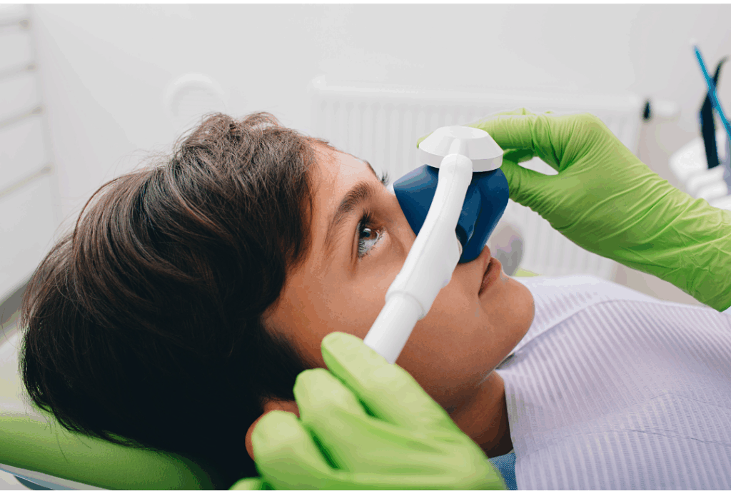 Dental assistant administering nitrous oxide via a nose mask to a young, relaxed patient, showcasing **Compassionate Sedation Dentistry** at Manassra Dental in San Jose, CA.