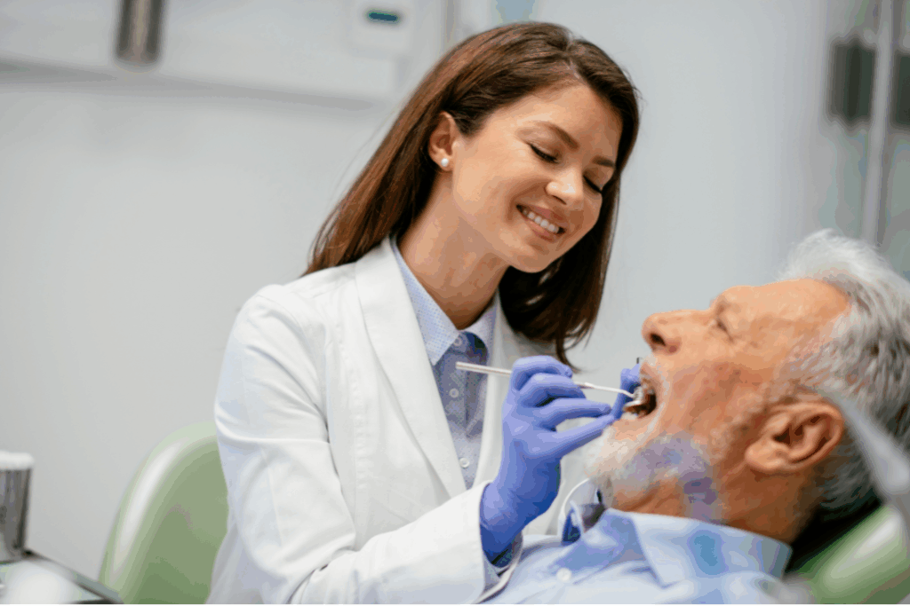 Smiling female dentist providing a thorough examination to an older patient, illustrating the **personalized patient experience** and compassionate care at Manassra Dental in San Jose, CA.