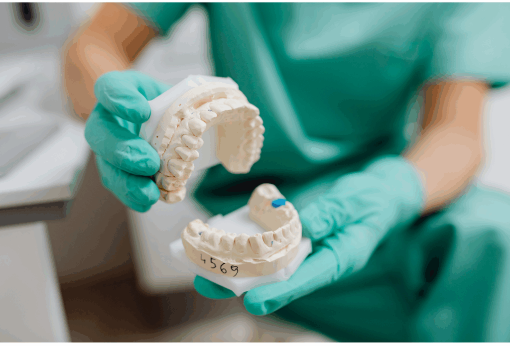 Dentist in San Jose holding a dental impression cast (mold) for custom **prosthodontics** work, including crowns, bridges, or dentures, at Manassra Dental.