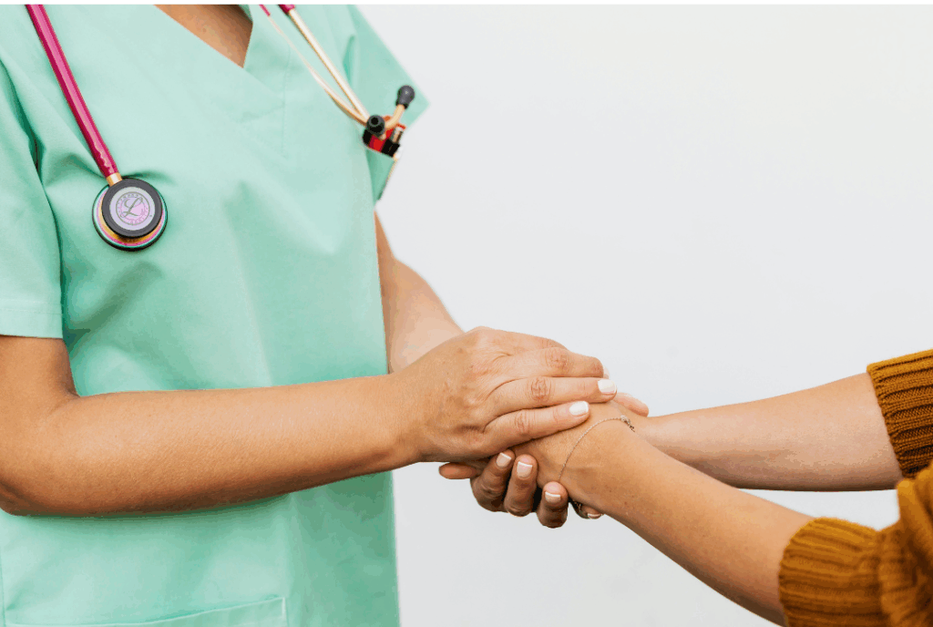Compassionate dental professional wearing scrubs holding a patient's hand for reassurance, illustrating supportive care for a **dental emergency** at Manassra Dental in San Jose.