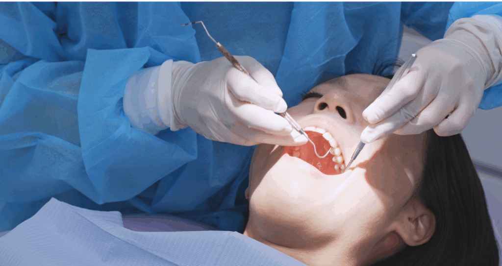 Dentist in surgical gown and gloves performing precise dental work on a patient, representing an **apicoectomy** procedure to save a tooth at Manassra Dental in San Jose.