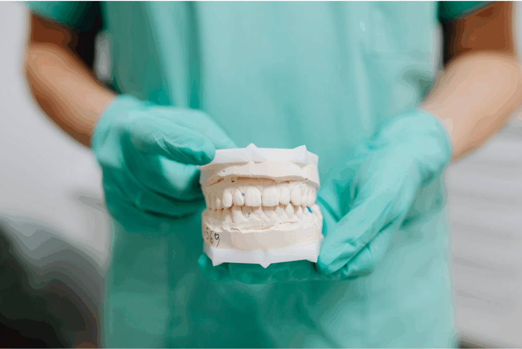 Dentist and patient reviewing a dental model and X-ray during a detailed **oral exam** consultation to discuss health and treatment options at Manassra Dental in San Jose.