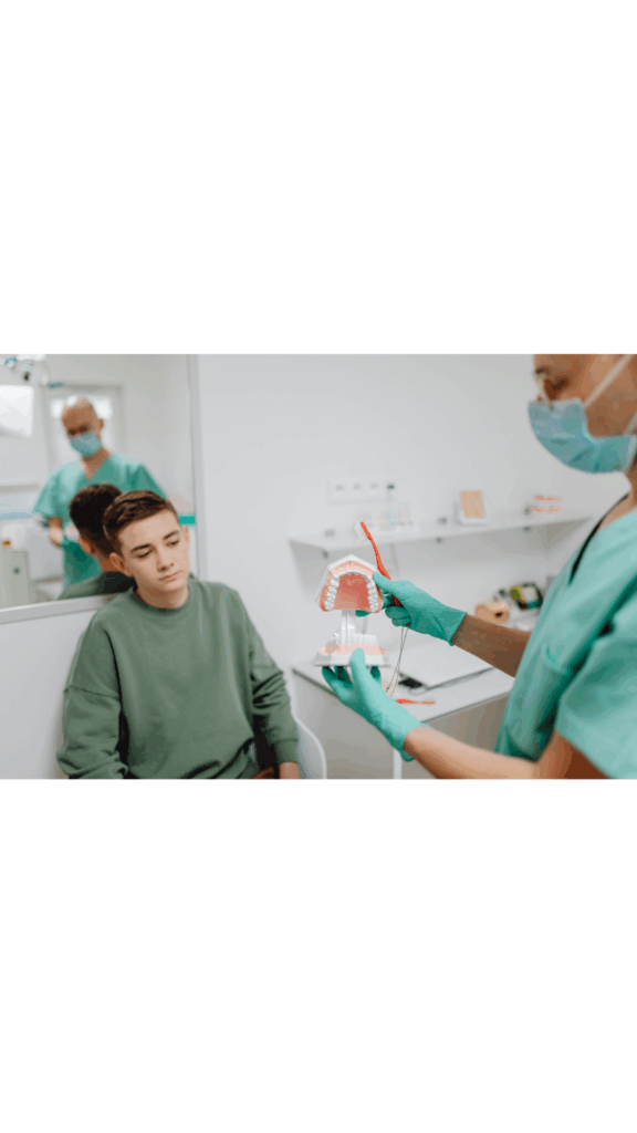 Dentist using a tooth model to explain dental health to a young patient, a part of understanding the issue during a **problem focused oral exam** at Manassra Dental in San Jose.