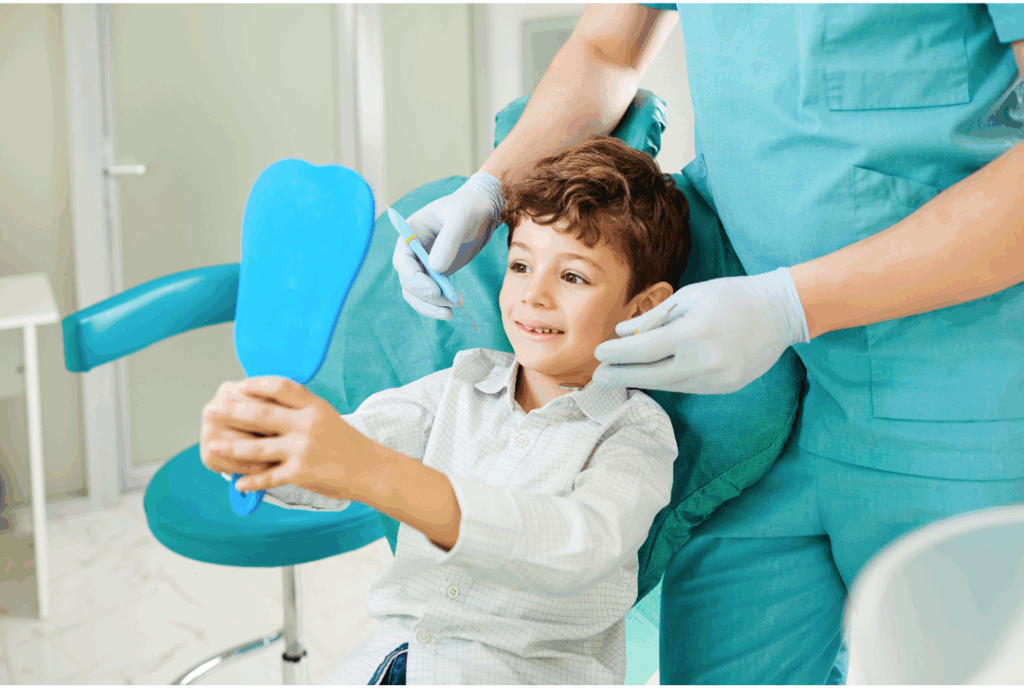 Smiling young boy looking in a mirror in a dental chair, experiencing positive and **kid-friendly dental care** at Manassra Dental in San Jose.