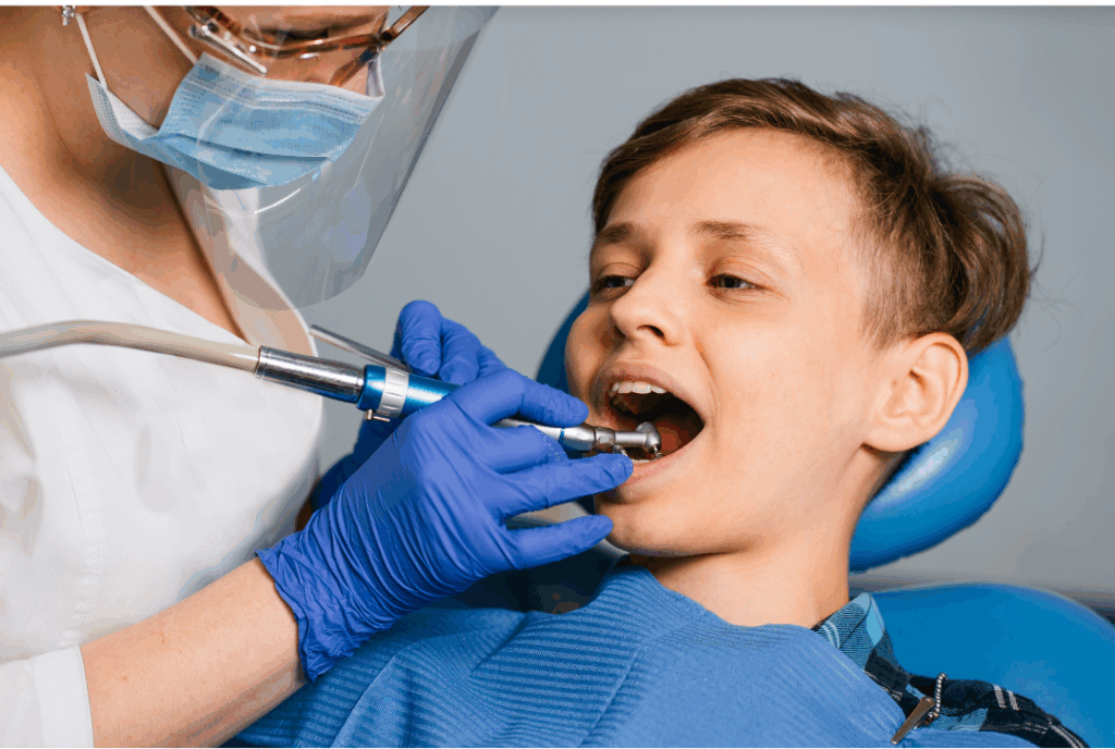 Dental professional performing a detailed examination or cleaning on a young male patient, highlighting precise **pediatric oral examinations** at Manassra Dental in San Jose.