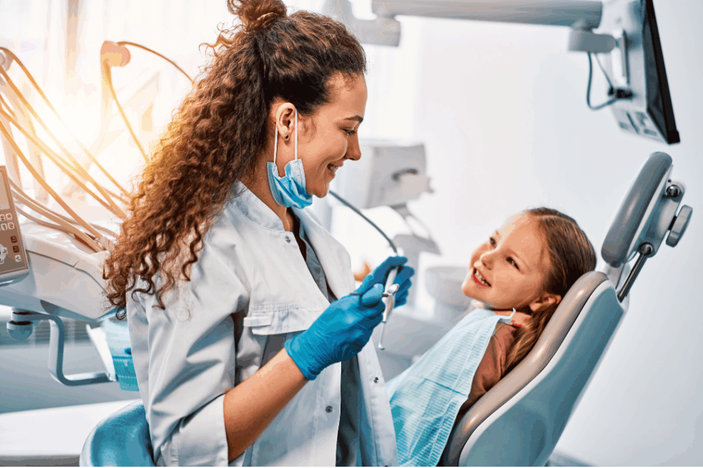 Caring female dentist reassuring a young girl in the dental chair, representing the gentle approach to **Pulpotomy and Pulpectomy** procedures at Manassra Dental in San Jose.
