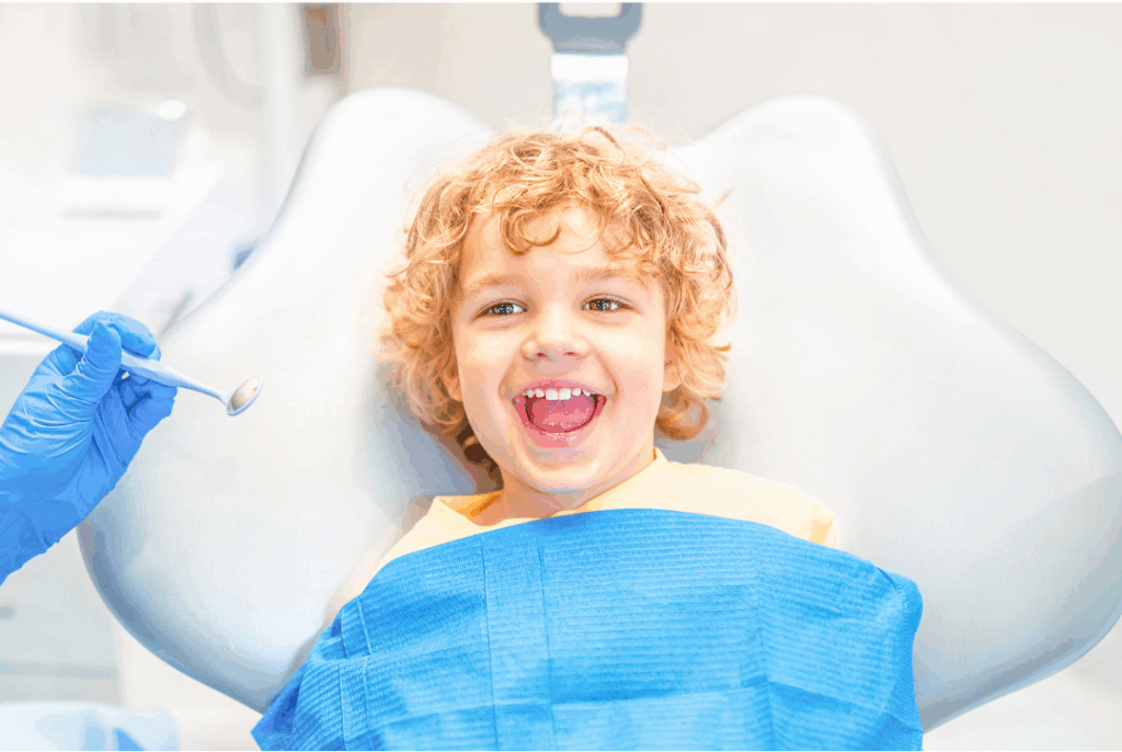 Happy young child opening their mouth wide during a gentle exam, representing the comfortable environment for **Frenectomy** procedures for lip or tongue ties at Manassra Dental in San Jose.