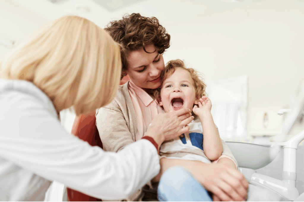 Dentist advising a mother holding a happy toddler, offering **tips for parents** on encouraging **healthy smiles at home** and home care routines at Manassra Dental in San Jose.