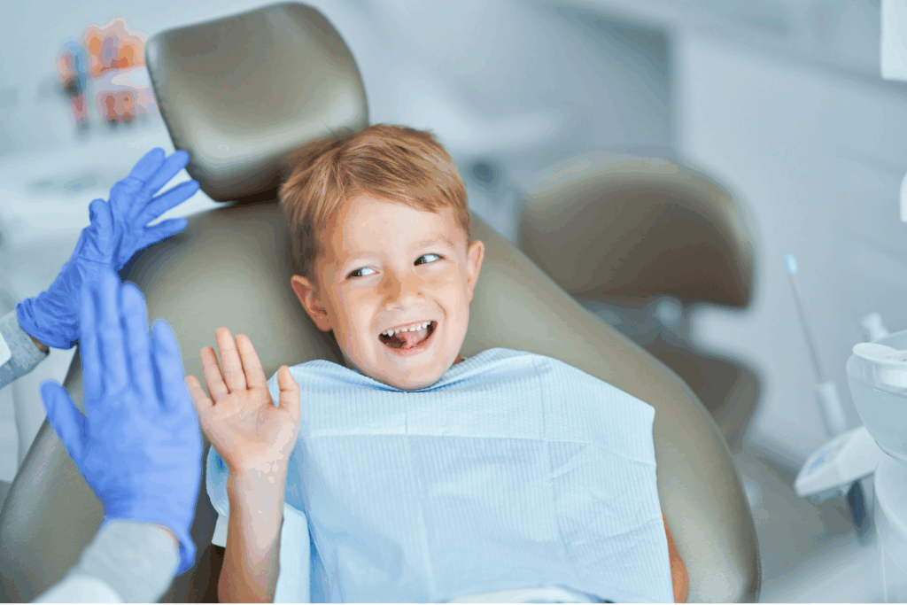Happy young boy giving a high-five to the dental professional, indicating a positive experience with **specialized pediatric dentistry concerns** and complex treatments at Manassra Dental in San Jose.