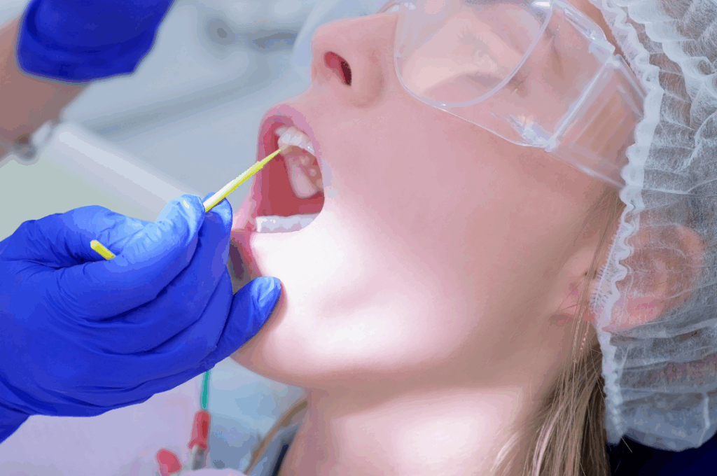 Dental professional applying professional **fluoride treatment** varnish to a patient's teeth using a small applicator, emphasizing **strengthened tooth enamel** and decay prevention at Manassra Dental in San Jose.