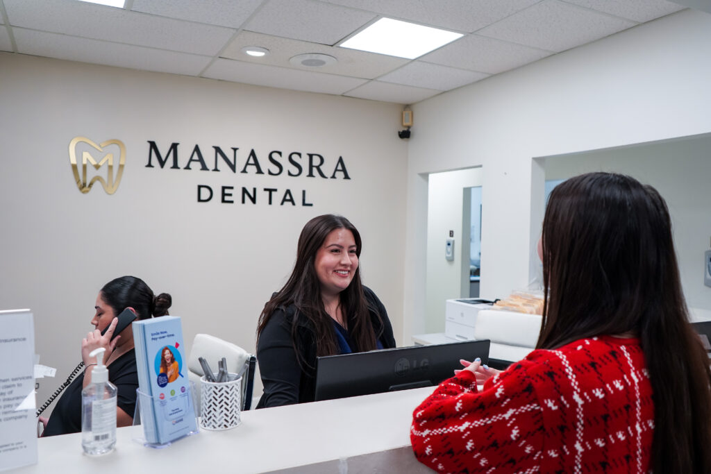 Front desk staff assisting a patient at the reception area of the dental office.