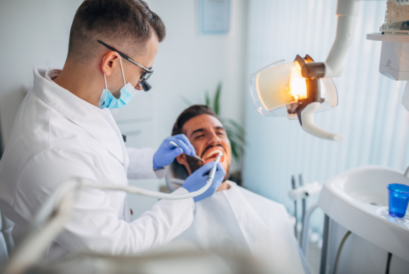A dentist at Manassra Dental in San Jose performing a comprehensive oral evaluation on a patient using professional diagnostic tools.