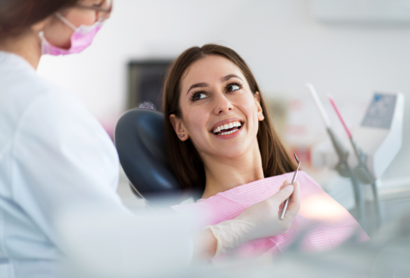 A happy patient at Manassra Dental in San Jose smiling during a routine periodic oral exam with a female dentist.
