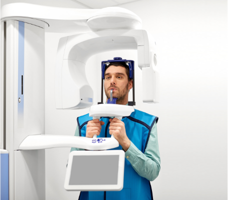 A patient at Manassra Dental undergoing a high-tech panoramic digital X-ray scan while wearing a protective lead vest.