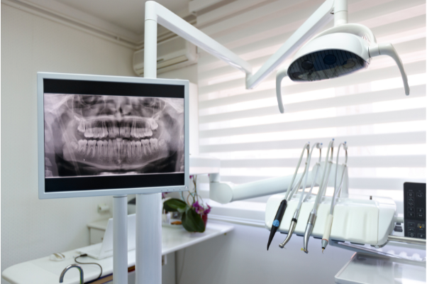 A modern dental operatory at Manassra Dental featuring a digital monitor displaying a high-resolution panoramic X-ray.