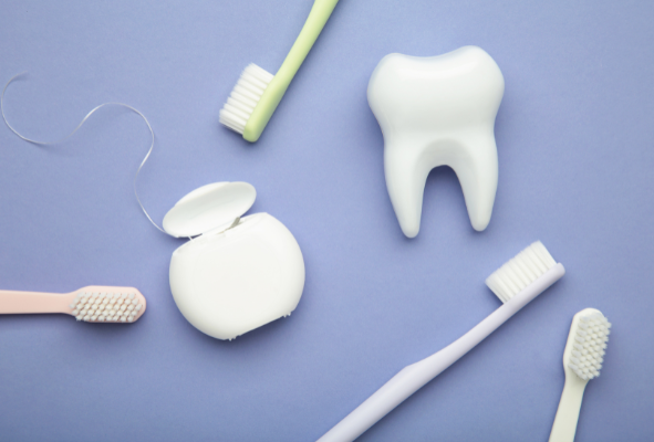 A stethoscope, tooth model, and toothbrush on a blue background, representing the importance of urgent dental care for overall health at Manassra Dental.