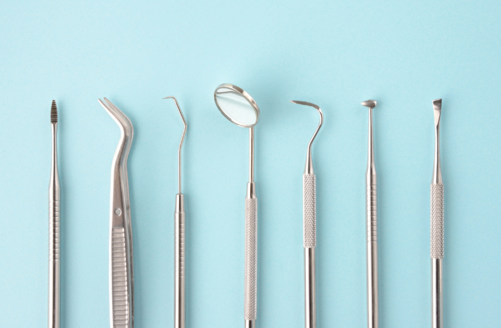 A row of professional stainless steel dental instruments, including a mirror and probes, on a blue background.