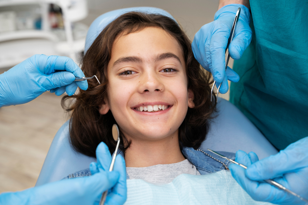 A young patient smiling in a dental chair while being examined by professionals at Manassra Dental